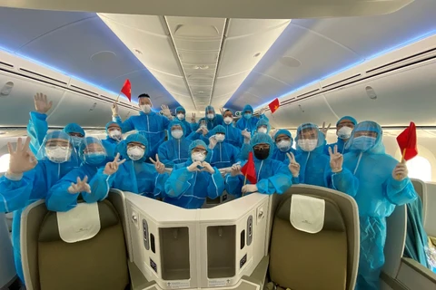 Toàn bộ phi hành đoàn Vietnam Airlines phải mặc quần áo bảo hộ toàn thân trong suốt quá trình phục vụ đưa người Việt Nam từ Mỹ về nước. (Ảnh: CTV/Vietnam+)