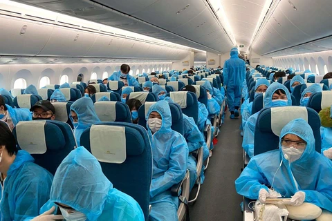 Tất cả hành khách được phát và phải mặc đồ bảo hộ trong suốt chuyến bay từ nước ngoài - nơi có dịch COVID-19 về Việt Nam. (Ảnh: CTV/Vietnam+)