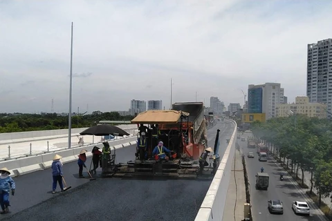 Nhà thầu đang tiến hành thi công thảm nhựa đường trên cầu cạn Mai Dịch-Nam Thăng Long. (Ảnh: Việt Hùng/Vietnam+)