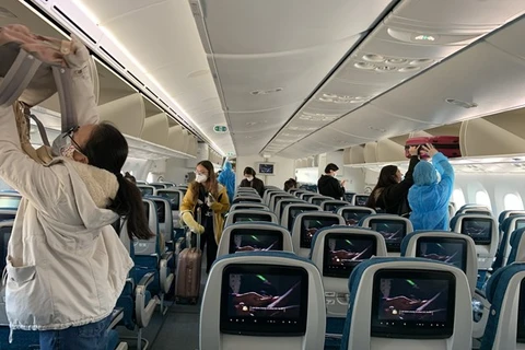 Hành khách trên chuyến bay của Vietnam Airlines thực hiện ngồi giãn cách ghế theo đúng quy định. (Ảnh: CTV/Vietnam+)