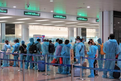 Hành khách trên chuyến bay quốc tế thương mại tới Việt Nam đầu tiên sau thời gian dài vì dịch COVID-19 làm thủ tục nhập cảnh tại sân bay Nội Bài. (Ảnh: CTV/Vietnam+)