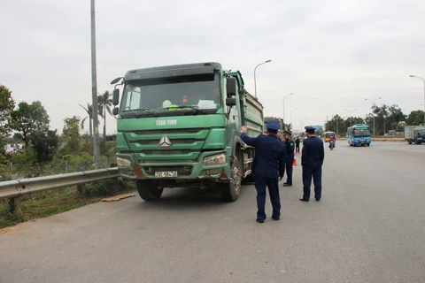 Lực lượng Thanh tra giao thông vận tải xử lý xe chở hàng quá tải trọng lưu thông qua cầu Thăng Long. (Ảnh: CTV/Vietnam+)