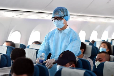 Tiếp viên Vietnam Airlines mặc đồ bảo hộ y tế trên chuyến bay để phòng chống dịch COVID-19. (Ảnh: CTV/Vietnam+)