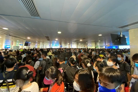 Hành khách xếp hàng dài chờ làm thủ tục lên máy bay tạ sân bay Tân Sơn Nhất. (Ảnh: CTV/Vietnam+)