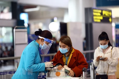 Nhân viên của hãng hàng không hướng dẫn khách làm thủ tục khai báo y tế trước khi vào điểm soi chiếu để lên tàu bay. (Ảnh: Huy Hùng/TTXVN)