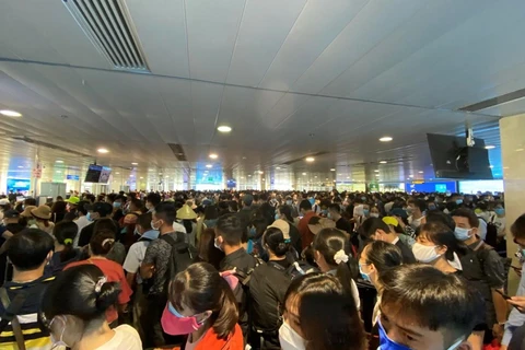 Hành khách xếp hàng dài chờ làm thủ tục lên máy bay tạ sân bay Tân Sơn Nhất. (Ảnh: CTV/Vietnam+)