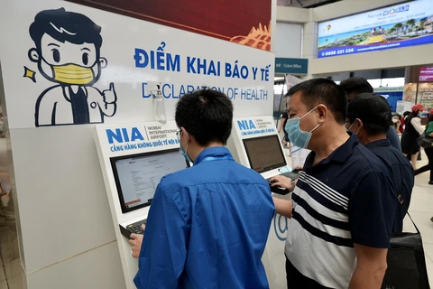 Sân bay Nội Bài bố trí nhân viên hỗ trợ khách khai báo y tế trực tuyến. (Ảnh: CTV/Vietnam+)
