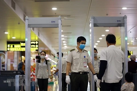 Nhân viên an ninh hàng không kiểm soát hành khách tại khu vực soi chiếu ở sân bay Nội Bài. (Ảnh: Huy Hùng/TTXVN)