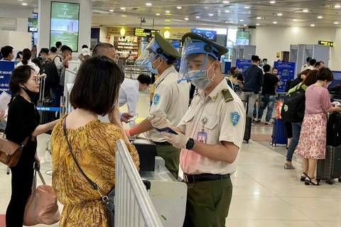 Lực lượng An ninh hàng không Nội Bài được trang bị đầy đủ găng tay, khẩu trang, tấm chắn giọt bắn trong khi tiếp xúc với hành khách. (Ảnh: CTV/Vietnam+)