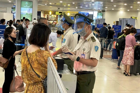 Lưc lượng an ninh hàng không tại sân bay Nội Bài kiểm soát thông tin hàng khách trước khi vào khu vực soi chiếu. (Ảnh: CTV/Vietnam+)