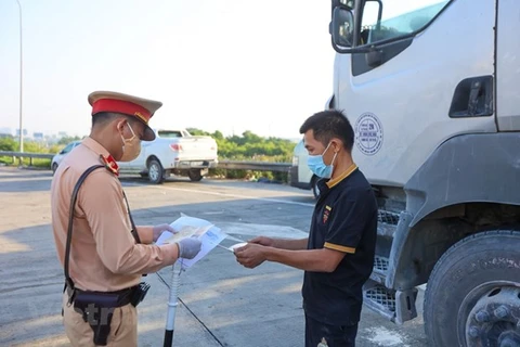 Cảnh sát giao thông kiểm tra bằng lái xe đối với tài xế xe chở hàng hóa. (Ảnh: Minh Sơn/Vietnam+)