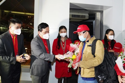 Giám đốc Điều hành Vietjet Đinh Việt Phương tặng hoa và lì xì may mắn cho hành khách trên chuyến bay đầu tiên của năm mới. (Ảnh: CTV/Vietnam+)