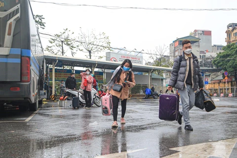 Hành khách xách đồ đạc sau chuyến trở về thành phố mệt nhoài vì ken cứng phương tiện. (Ảnh: Việt Hùng/Vietnam+)
