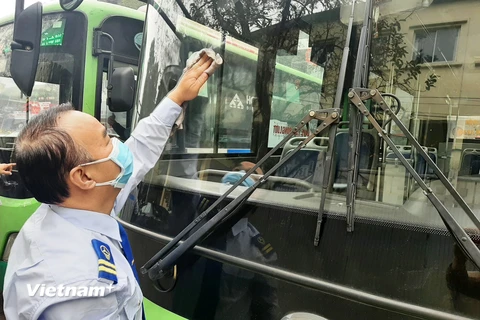 Anh Hồ Xuân Phong, lái xe tuyến số 33 thuộc Xí Nghiệp Tân Đạt đang vệ sinh xe sau hành trình đón khách. (Ảnh: Việt Hùng/Vietnam+)