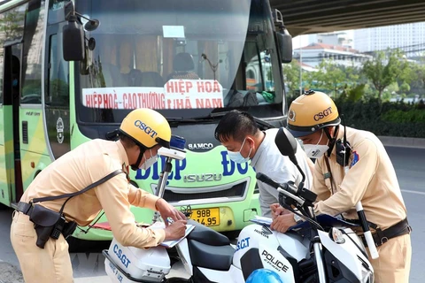 Cán bộ Đội cảnh sát giao thông số 6 lập biên bản xử lý tài xế xe khách với lỗi dừng đỗ, đón trả khách sai quy định tại tuyến đường Phạm Hùng. (Ảnh: Phạm Kiên/TTXVN)