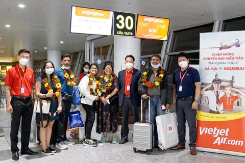 Lãnh đạo và phi hành đoàn Vietjet chào đón những hành khách trên chuyến bay đầu tiên từ Hà Nội đến Mumbai. (Ảnh: CTV/Vietnam+)