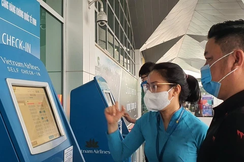 Nhân viên Vietnam Airlines hướng dẫn giúp hành khách làm thủ tục trực tuyến tại Kios check-in online ở một sân bay. (Ảnh: CTV/Vietnam+)