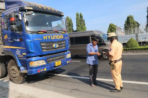 Tổ cảnh sát giao thông kiểm tra chủ phương tiện điều khiển xe trên Quốc lộ 1 thuộc huyện Châu Thành, tỉnh Tiền Giang. (Ảnh: Minh Trí/TTXVN)