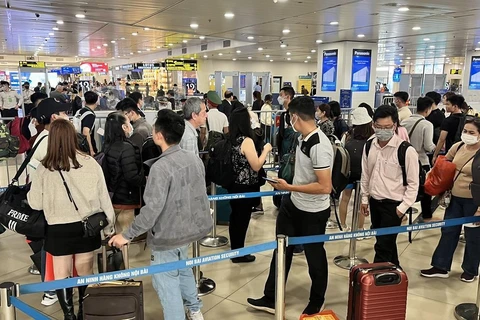 Hành khách xếp hàng dài chờ vào khu vực kiểm tra giấy tờ tùy thân và soi chiếu an ninh tại sân bay Nội Bài. (Ảnh: CTV/Vietnam+)