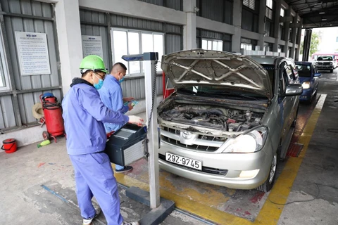 Nhân viên đăng kiểm thực hiện quy trình kiểm định xe cơ giới tại một trung tâm đăng kiểm ở Hà Nội. (Ảnh: Minh Hiếu/Vietnam+)