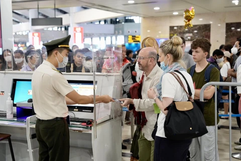 Nhân viên an ninh hàng không kiểm tra giấy tờ tùy thân của hành khách làm thủ tục đi máy bay. (Ảnh: CTV/Vietnam+)