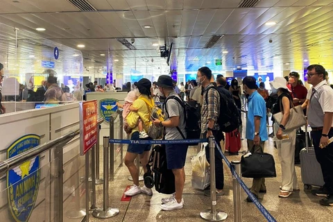 Nhân viên an ninh hàng không kiểm tra giấy tờ thủ tục bay của hành khách trước khi vào điểm soi chiếu an ninh. (Ảnh: CTV/Vietnam+)