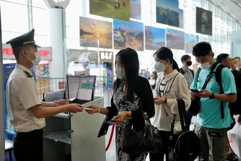 Nhân viên an ninh hàng không kiểm tra giấy tờ tùy thân khi làm thủ tục chuyến bay của hành khách. (Ảnh: CTV/Vietnam+)