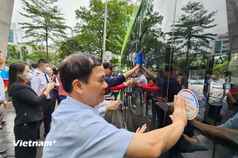 Các đại biểu dán các khẩu hiệu tuyên truyền trên xe buýt điện nhằm ủng hộ Tuần lễ An toàn giao thông đường bộ toàn cầu lần thứ 7. (Ảnh: Việt Hùng/Vietnam+)