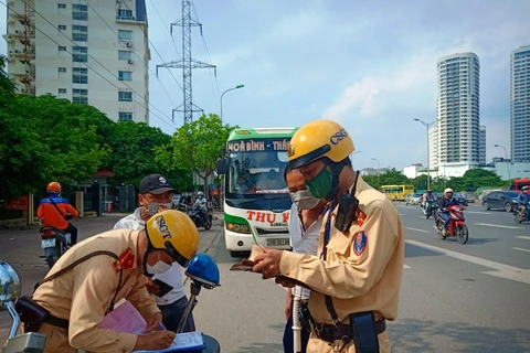 Lực lượng Cảnh sát giao thông xử phạt chủ phương tiện xe khách vi phạm giao thông. (Ảnh: PV/Vietnam+)