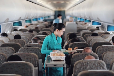Tiếp viên của Hãng hàng không Vietnam Airlines phục vụ suất ăn trên chuyến bay. (Ảnh: CTV/Vietnam+)