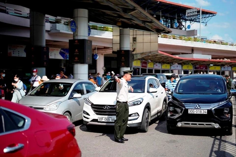 Nhân viên an ninh hàng không phân làn phương tiện đi vào làn đỗ tại Nhà ga T1 Sân bay Quốc tế Nội Bài. (Ảnh: CTV/Vietnam+