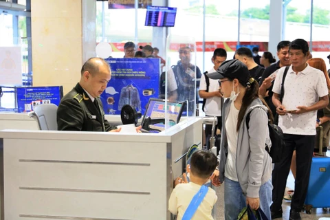 Nhân viên an ninh hàng không kiểm tra giấy tờ hành khách làm thủ tục chuyến bay. (Ảnh: PV/Vietnam+)