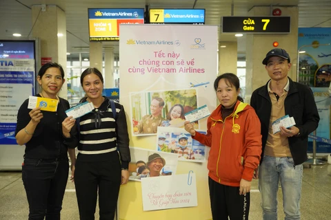 Người lao động cầm tấm vé bay và được được chuyên chở miễn phí trên chuyến bay của Vietnam Airlines. (Ảnh: PV/Vietnam+)