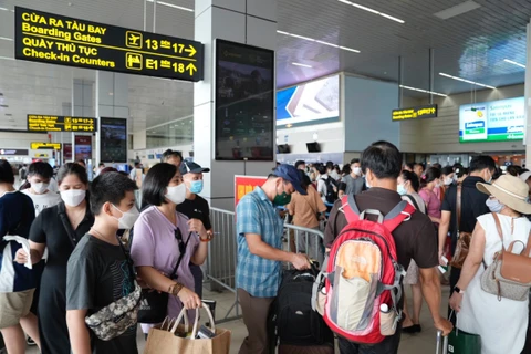 Hành khách xếp hàng làm thủ tục an ninh soi chiếu hàng không trước khi lên máy bay. (Ảnh: PV/Vietnam+)