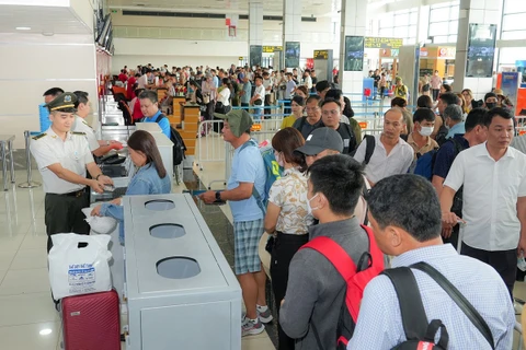 Nhân viên an ninh hàng không kiểm tra giấy tờ hành khách làm thủ tục đi máy bay. (Ảnh: PV/Vietnam+)