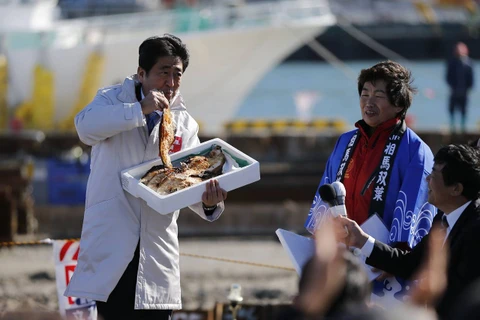 Thủ tướng Nhật Bản Shinzo Abe ăn một con cá nướng tại cảng cá Soma Haragama ở tỉnh Fukushima. (Nguồn: Reuters)