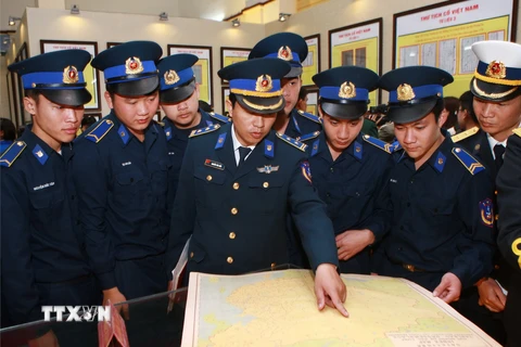 Cán bộ, chiến sỹ tìm hiểu tư liệu và bản đồ tại triển lãm. (Ảnh: Lâm Khánh/TTXVN)