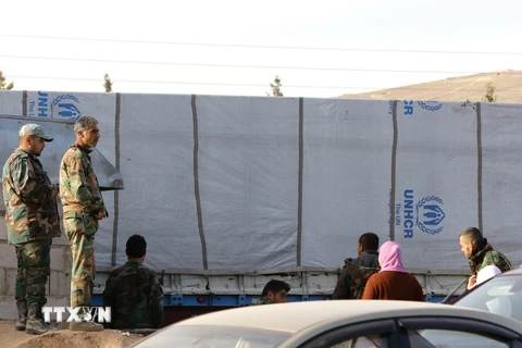 Lực lượng chính quyền Syria bên các xe chở hàng cứu trợ tại Moadimayet al-Sham ngày 17/2. (Nguồn: AFP/TTXVN)