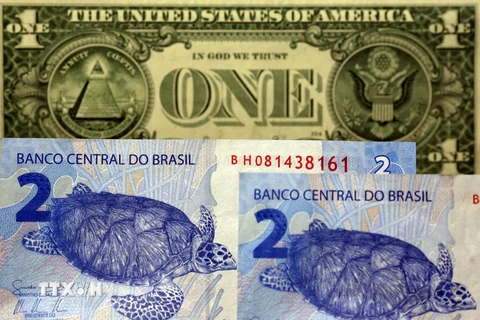 Đồng tiền giấy Brazil mệnh giá 2 real (dưới) và đồng đôla Mỹ mệnh giá 1USD. (Nguồn: Reuter/TTXVN)