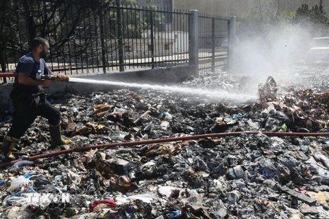 Nhân viên cứu hỏa phun nước dập các đám cháy sau khi người biểu tình đốt rác thải bị ứ đọng trên một đường phố ở Beirut. (Nguồn: AFP/TTXVN)