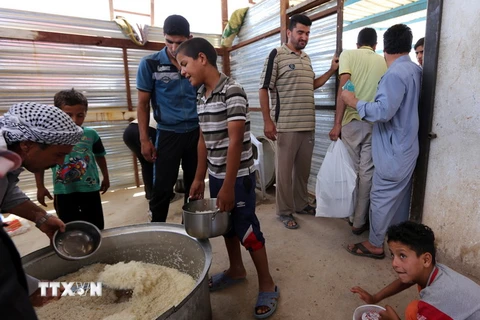 Trẻ em Iraq xếp hàng nhận lương thực cứu trợ tại khu vực Dora, ngoại ô thủ đô Baghdad ngày 31/5, sau khi phải rời bỏ nhà cửa ở khu vực chiến sự. (Nguồn: AFP/TTXVN)