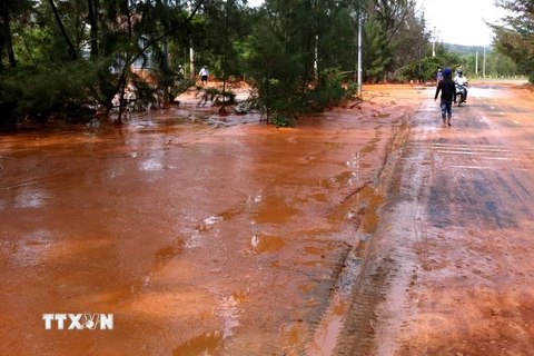 Nước bùn đỏ chảy tràn ra đường sau khi hồ chứa nước thải titan tại Bình Thuận bị vỡ hồi tháng 11/2013. (Ảnh Nguyễn Thanh/TTXVN)
