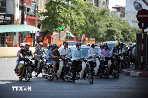Người dân chen chân trong bóng mát khi chờ đèn xanh giao thông tại Hà Nội. (Ảnh: Quang Quyết/TTXVN)