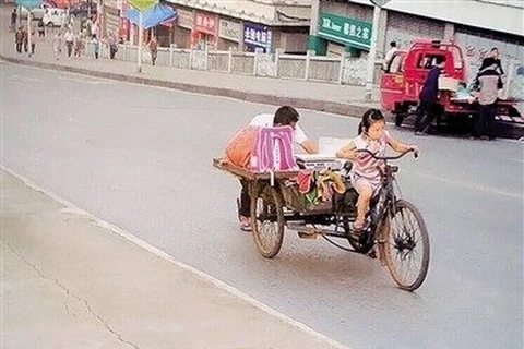 Cô bé Yangyang 7 tuổi gò lưng đạp xe ba bánh. (Nguồn: CCTVNews)