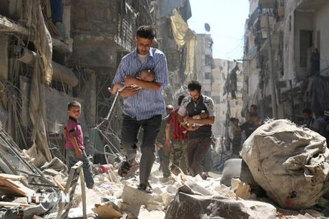 Sơ tán các em nhỏ Syria ra khỏi một tòa nhà bị sập sau vụ không kích nhằm ở thành phố Aleppo. (Nguồn: AFP/TTXVN)
