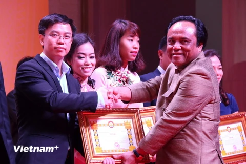 Phó Chủ tịch Hội đồng Thương mại và Công nghiệp Quốc gia Lào trao bằng khen cho đại diện Tập đoàn Cao su Việt Nam tại Lào. (Ảnh: Phạm Kiên/Vietnam+)