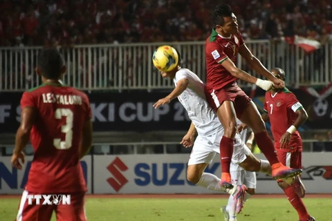 Pha tranh bóng quyết liệt giữa cầu thủ hai đội tuyển Việt Nam và Indonesia trong trận đấu bán kết lượt đi. (Nguồn: AFP/TTXVN)