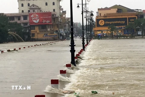 Mưa lũ gây ngập lụt tiềm ẩn nhiều nguy hiểm khi người dân di chuyển ở Huế. (Ảnh: Quốc Việt/TTXVN)
