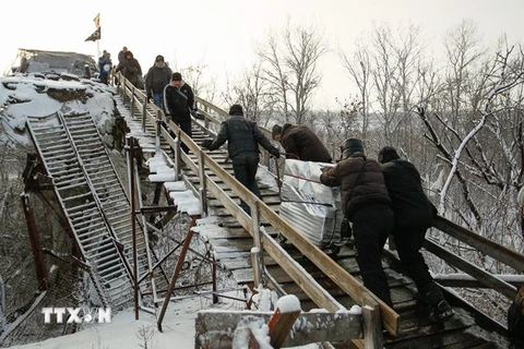 Người dân đi qua chốt kiểm soát giữa quân đội Ukraine và lực lượng đòi độc lập bằng chiếc thang gỗ thay thế cho chiếc cầu bị phá hủy trong một đợt giao tranh ở khu vực Luhansk ngày 16/12. (Nguồn: EPA/TTXVN)