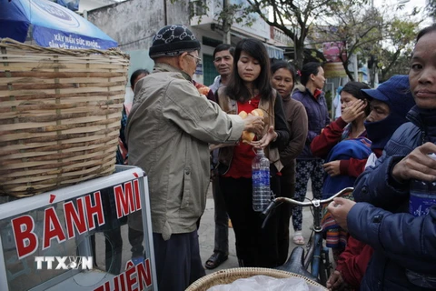 Cụ Bình phát bánh mì từ thiện cho người nhà bệnh nhân tại bệnh viện đa khoa tỉnh Kon Tum. (Ảnh: Hồng Điệp/TTXVN)